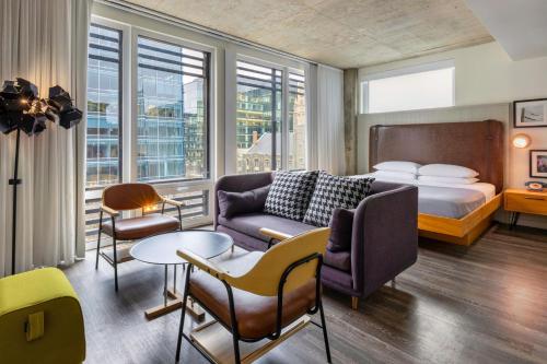 a hotel room with a bed and a couch and chairs at Moxy Washington, DC Downtown in Washington