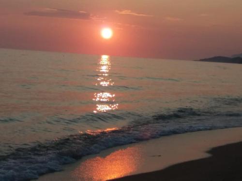 a sunset on the beach with the sun setting at LEMONELIA, one big,4-5 people and one small apartment ,2-3 people in Loutsa