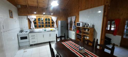 cocina con mesa y cocina con electrodomésticos blancos en Cabaña Ayelen en Esquel