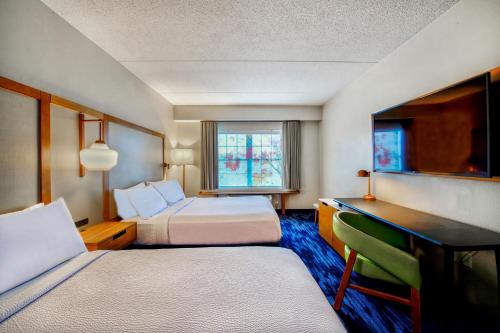 a hotel room with two beds and a desk at Fairfield Inn & Suites by Marriott Cortland in Cortland