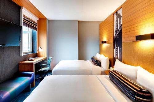 a hotel room with two beds and a couch at Aloft Brooklyn in Brooklyn