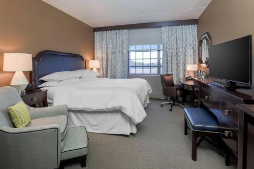 a hotel room with a bed and a desk and a television at Sheraton Tarrytown Hotel in Tarrytown