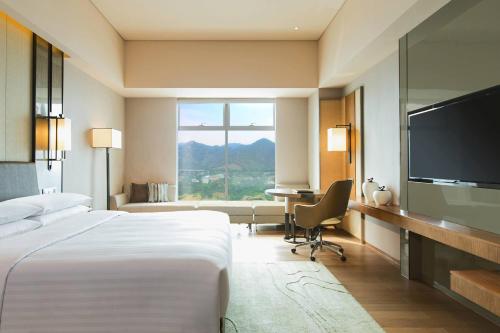um quarto de hotel com uma cama, uma secretária e uma televisão em Chongqing Marriott Hotel em Chongqing