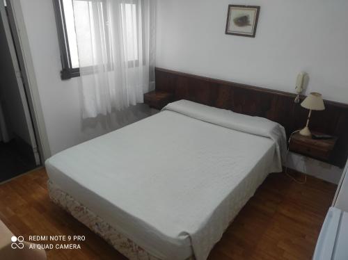 um quarto com uma cama branca num quarto em Necochea Real Hotel em Necochea