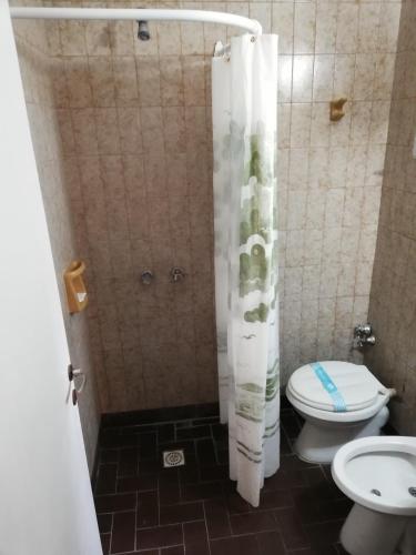 uma casa de banho com um chuveiro, um WC e uma cortina de chuveiro. em Necochea Real Hotel em Necochea