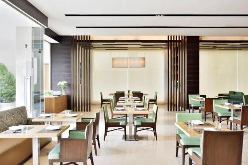 un restaurante con mesas de madera y sillas verdes en Fairfield by Marriott Indore, en Indore