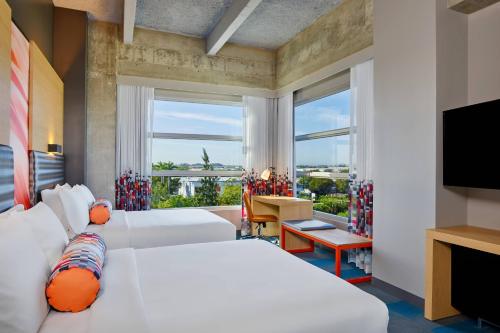 a hotel room with two beds and a television at Aloft Miami Airport in Miami