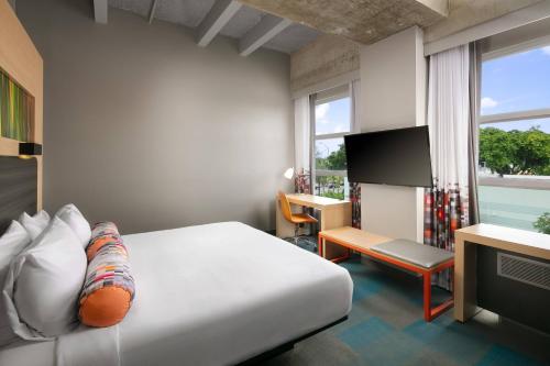 a hotel room with a bed and a tv at Aloft Miami Airport in Miami
