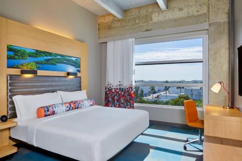a bedroom with a large white bed and a large window at Aloft Miami Airport in Miami