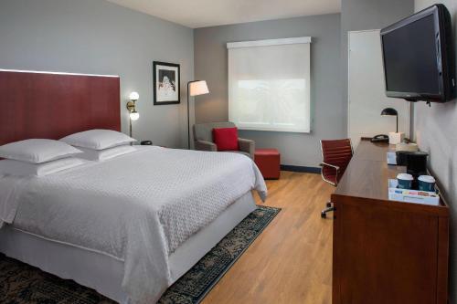 a bedroom with a bed and a flat screen tv at Four Points by Sheraton Houston Hobby Airport in Houston