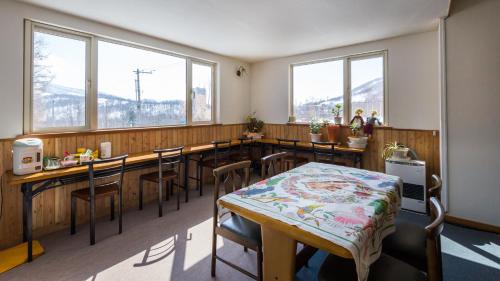 a dining room with a table and chairs and windows at Lodge Romulus in Rusutsu
