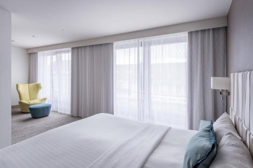 um quarto com uma cama grande e uma cadeira amarela em Courtyard by Marriott Munich City Center em Munique