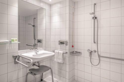 y baño blanco con lavabo y ducha. en Courtyard by Marriott Munich City Center en Múnich