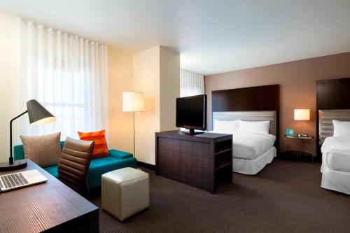 a hotel room with a bed and a desk with a tv at Aloft Silicon Valley in Newark