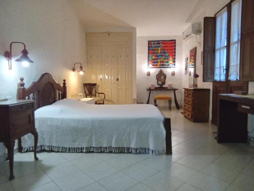 Un dormitorio con una gran cama blanca y una mesa en Casa rústica en Santiago del Estero