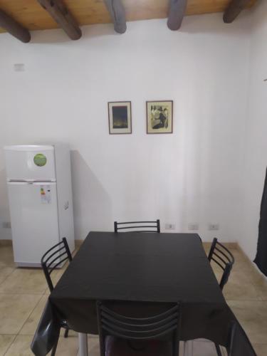 a black table and chairs in a kitchen with a refrigerator at Departamentos Anchorena #5 in Ciudad Lujan de Cuyo