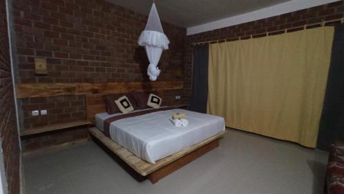a bedroom with a bed and a brick wall at Bunga Maliq Bungalow Lombok in Tetebatu