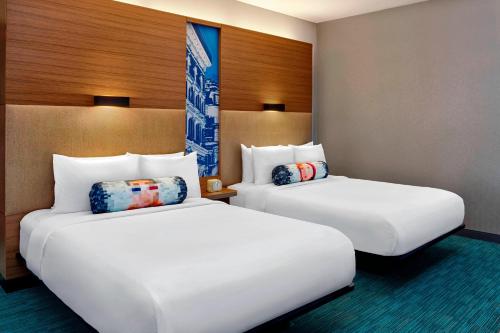 two beds sitting next to each other in a room at Aloft Montreal Airport in Dorval