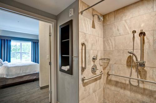 a bathroom with a walk in shower next to a bed at Residence Inn by Marriott Hamilton in Hamilton