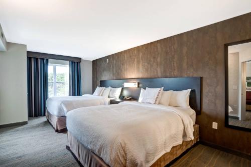 a hotel room with two beds and a mirror at Residence Inn by Marriott Hamilton in Hamilton