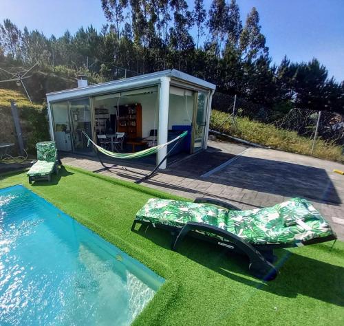 a house with a hammock next to a pool at Casa Rocha Velha con piscina y terraza particular in Santiago de Compostela