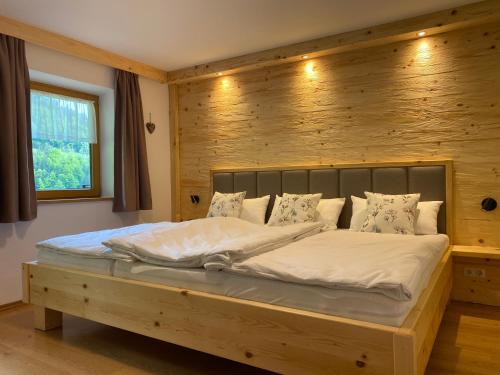 1 dormitorio con 1 cama grande y pared de madera en Wimbachlehen, en Ramsau