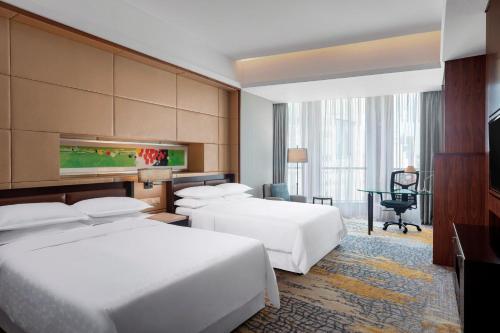 um quarto de hotel com duas camas e uma secretária em Sheraton Grand Shanghai Pudong Hotel & Residences em Xangai