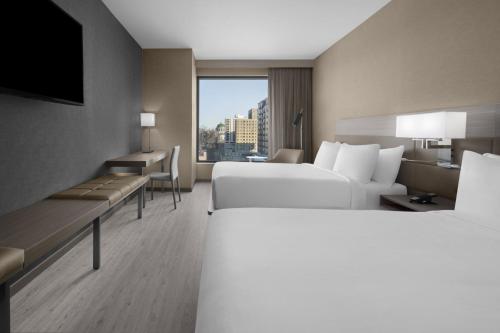 AC Hotel by Marriott St Louis Central West End في سانت لويس: غرفة فندقية بسريرين ونافذة