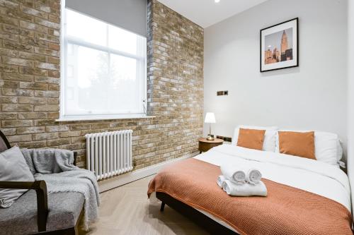 a bedroom with a bed and a brick wall at Khayat Homes - Kings Cottage in London