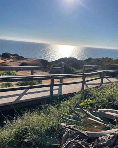a wooden path next to the ocean with a fence at Jasmine Beachouse in Lagos