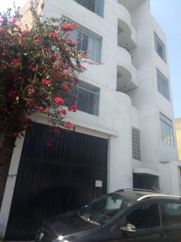 un coche negro estacionado frente a un edificio blanco en RESIDENCIAL SALAMANCA, en Lima