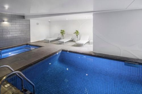 a swimming pool in a building with chairs at Swainson on Hindmarsh in Adelaide