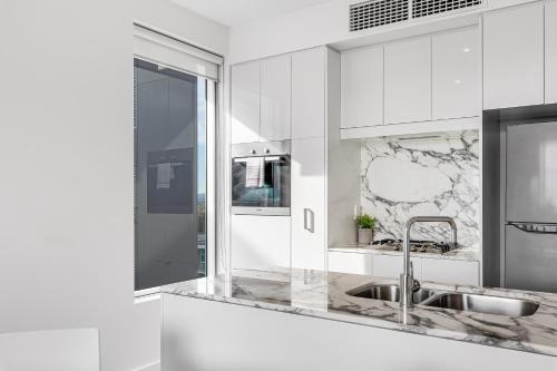 a white kitchen with a sink and a mirror at Swainson on Hindmarsh in Adelaide