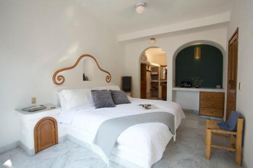 ein weißes Schlafzimmer mit einem großen Bett und einem Stuhl in der Unterkunft La villa del sol - pool & spa and staff in Puerto Vallarta
