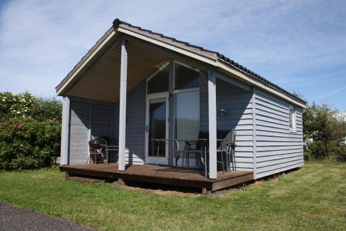 a small house with a porch and a deck at Løkken Family Camping & Guesthouse in Løkken