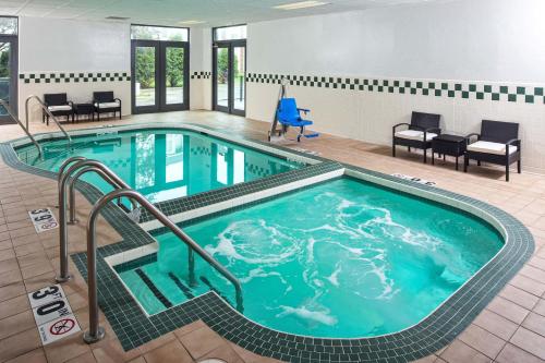 a pool in a hotel room with chairs and a table at Four Points by Sheraton Appleton in Appleton