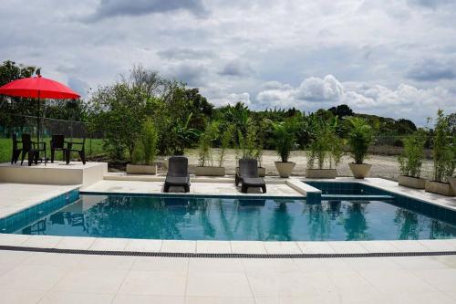 - une piscine avec 2 chaises et un parasol rouge dans l'établissement Villa Santho, 