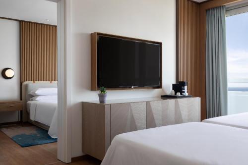 a hotel room with a flat screen tv and two beds at Sheraton Grand Tel Aviv in Tel Aviv