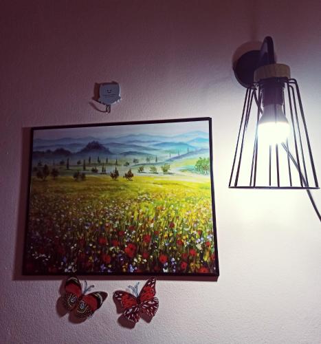 a painting of a field with butterflies hanging on a wall at New Garden View GF Double Room FREE parking in Batu Unjor