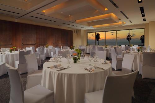 a room with white tables and white chairs and a room with tables and white tables at Sheraton Grand Tel Aviv in Tel Aviv