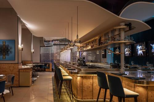 a restaurant with a bar with chairs and tables at Sheraton Grand Tel Aviv in Tel Aviv