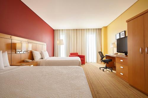 a hotel room with two beds and a flat screen tv at Courtyard by Marriott Leon at The Poliforum in León
