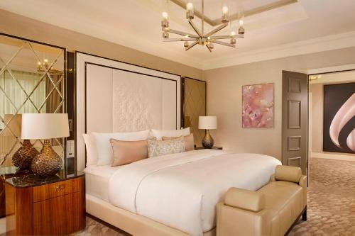 a bedroom with a large white bed and a chandelier at The Ritz-Carlton, Berlin in Berlin