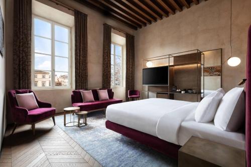 ルッカにあるGrand Universe Lucca, Autograph Collectionの大きなベッドと椅子が備わるホテルルームです。
