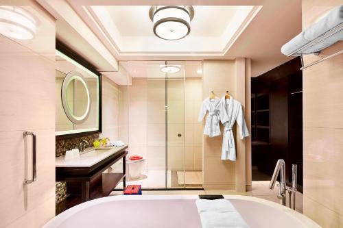 La salle de bains est pourvue d'une baignoire, d'un lavabo et d'une douche. dans l'établissement Sheraton Bali Kuta Resort, à Kuta