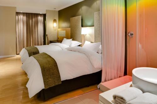 a bedroom with a large bed and a bathroom at Protea Hotel by Marriott Bloemfontein Willow Lake in Bloemfontein