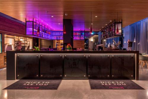 a bar in a restaurant with purple lighting at Moxy Frankfurt Airport in Frankfurt