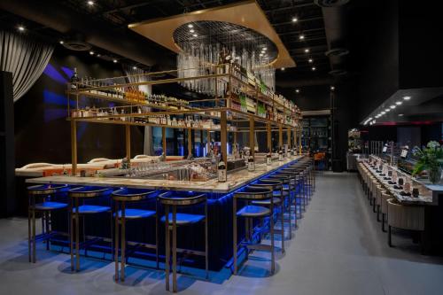 a bar with blue stools in a room at The ENGLiSH Hotel, Las Vegas, a Tribute Portfolio Hotel in Las Vegas