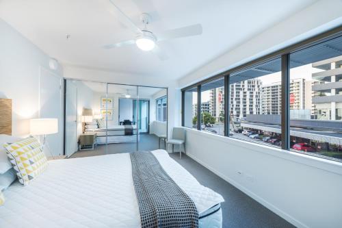 a bedroom with a large bed and large windows at Link Portside Wharf Apartment Hotel in Brisbane