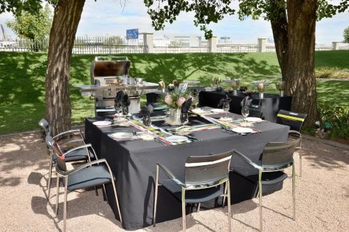 a table with a black tablecloth and chairs under a tree at Protea Hotel by Marriott O R Tambo Airport in Kempton Park